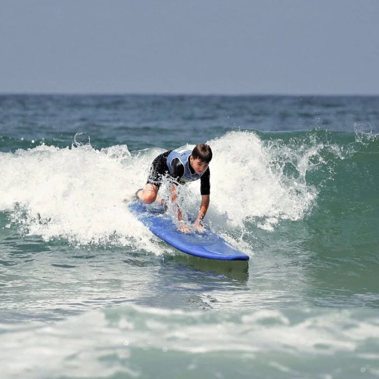 Un adolescent se lève sur sa planche de surf.