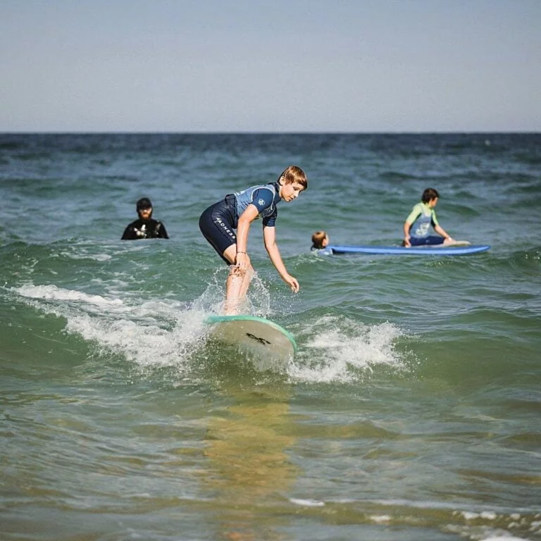 Un adolescent debout sur une planche de surf, en train de surfer une petite vague.