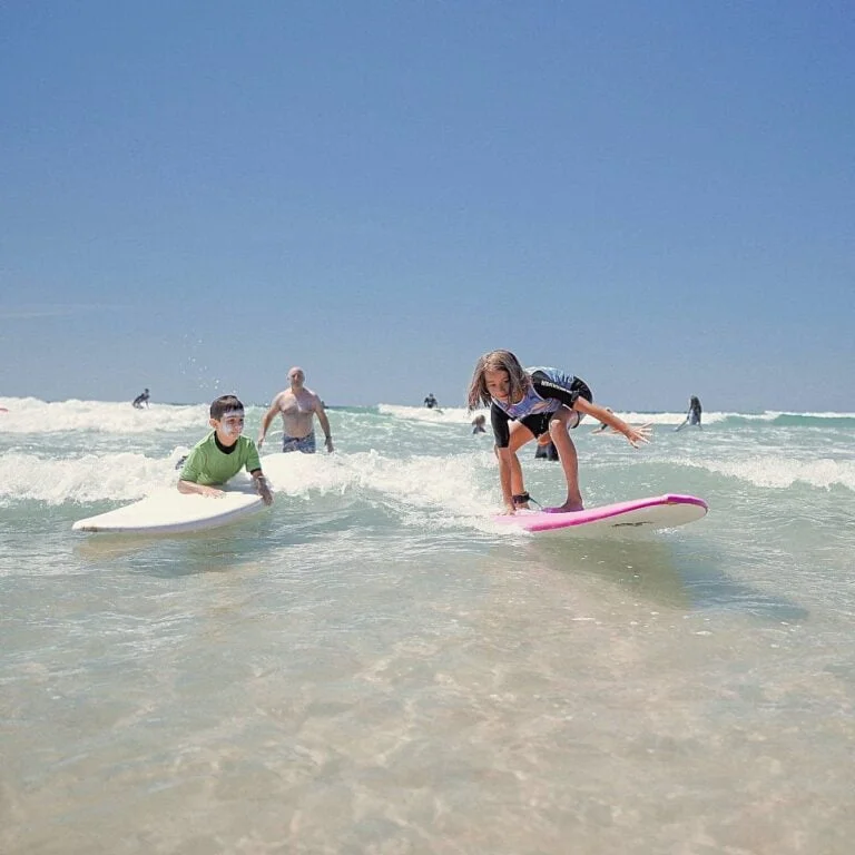 Un garçon et une fillette font du surf en eau peu profonde.