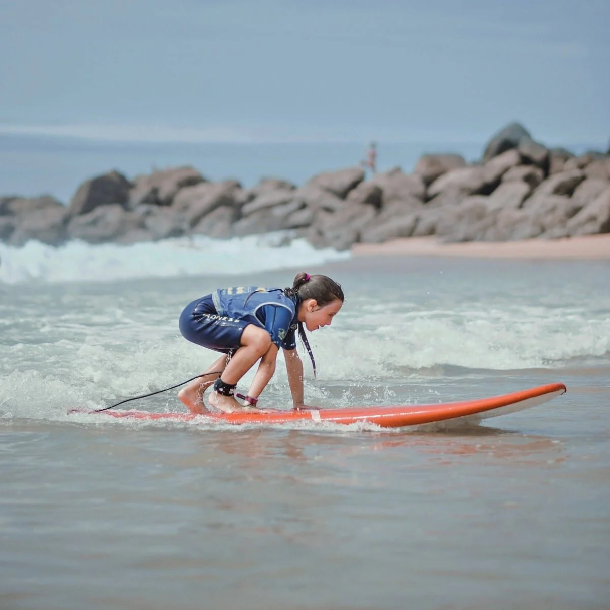 Une fillette apprend à se lever sur sa planche.