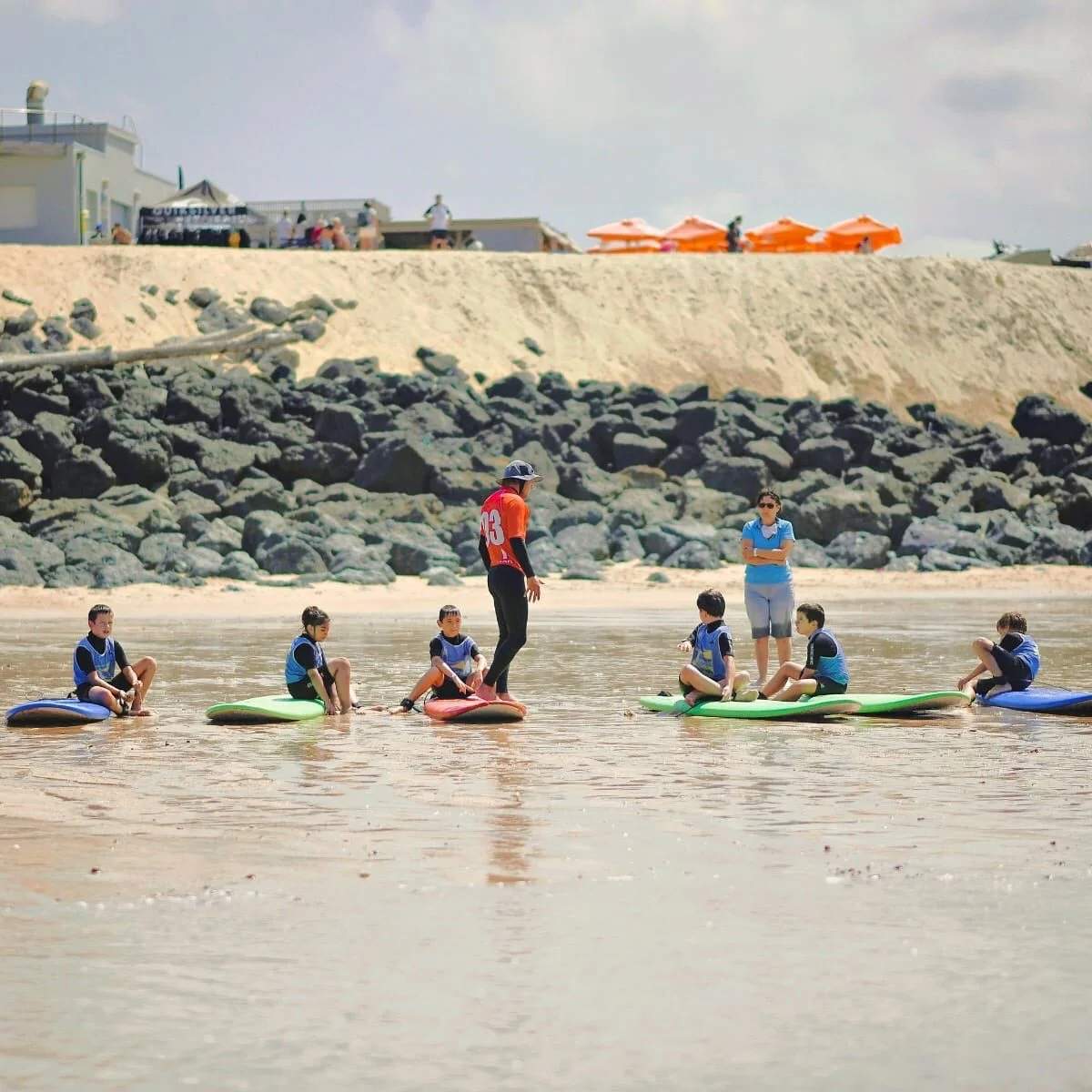 Un moniteur de l’école Capbreton Surfer donne un cours de surf à un groupe d’enfants sur la plage.