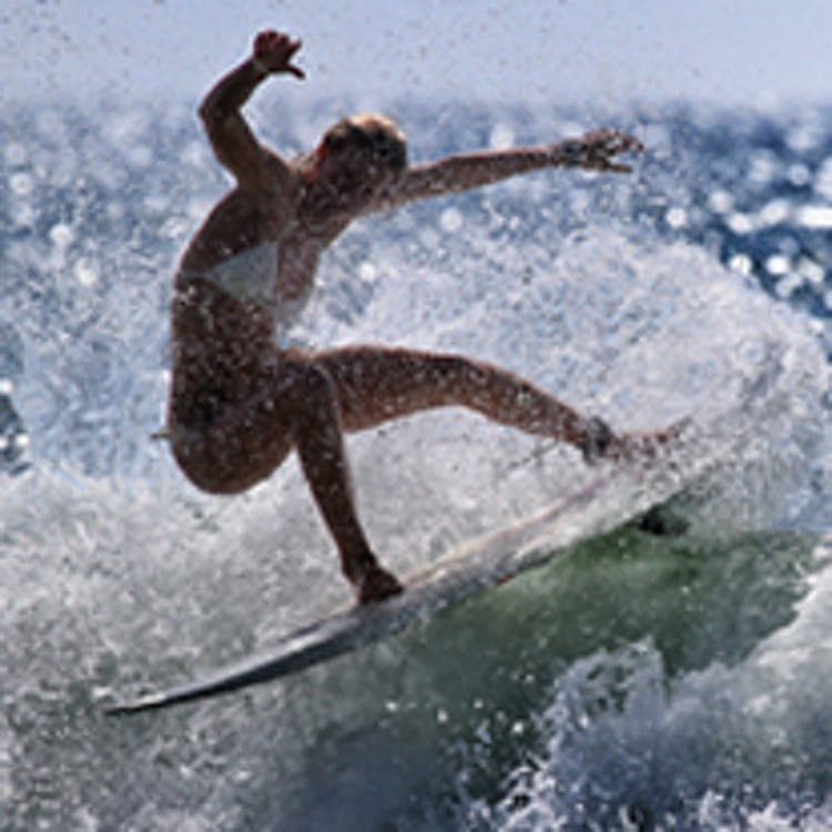 Une jeune femme en maillot surfe sur une belle vague d’été.